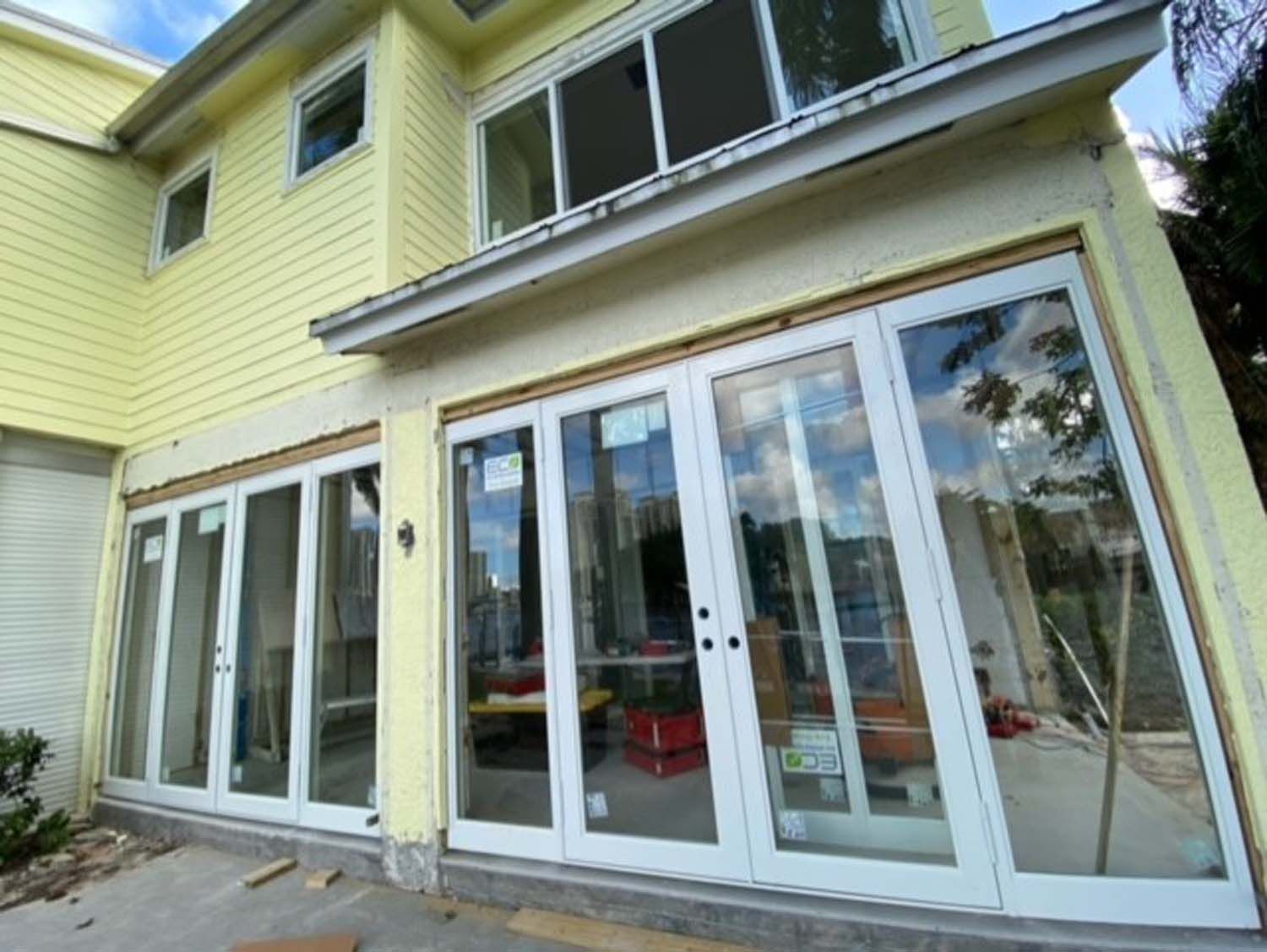 A yellow house with a lot of windows and sliding glass doors.