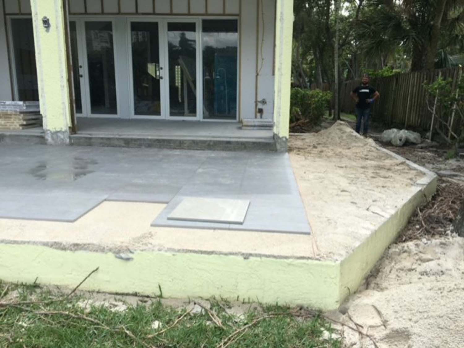 A man is standing in front of a house that is being remodeled.