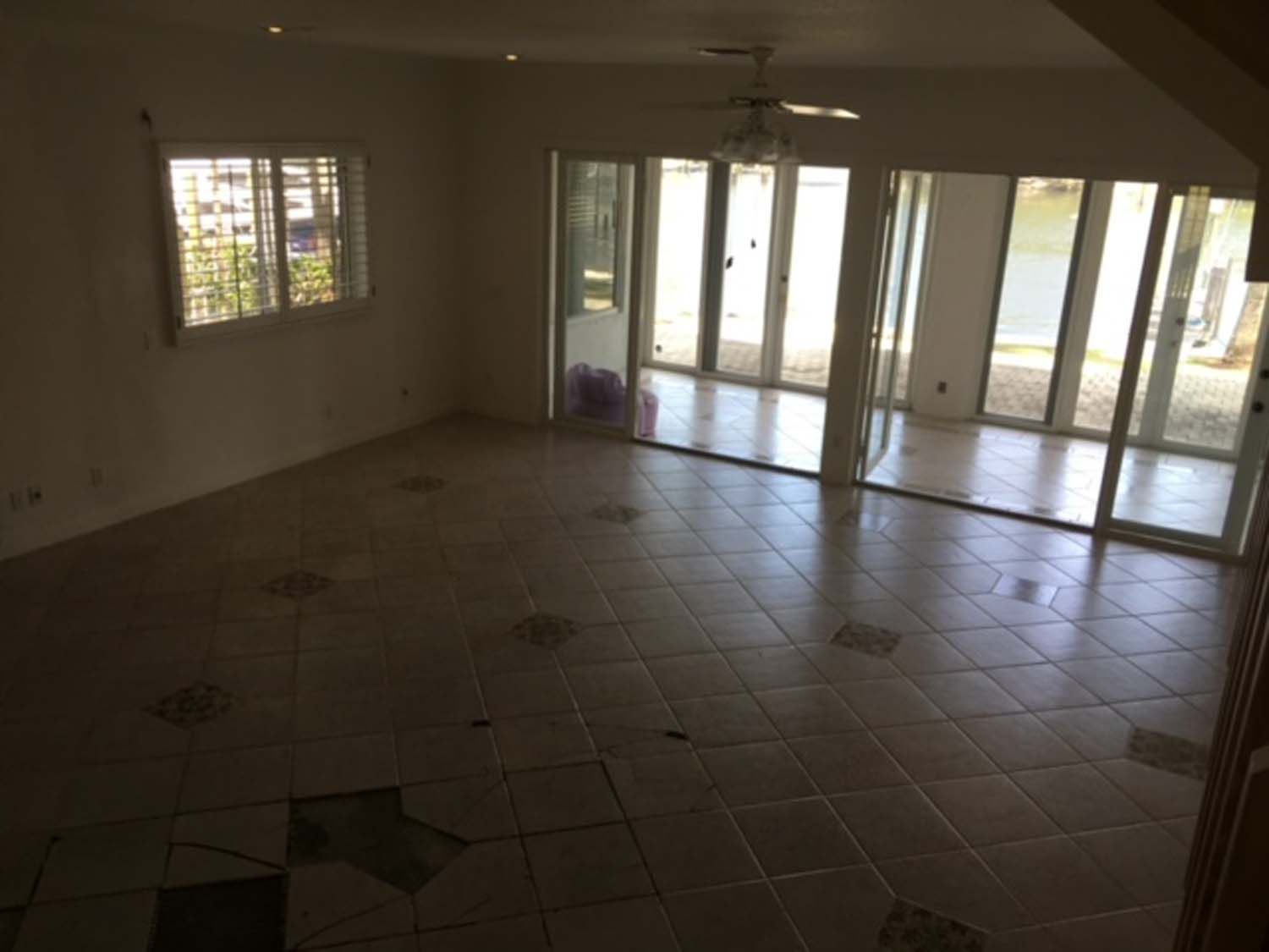 An empty living room with sliding glass doors and a ceiling fan
