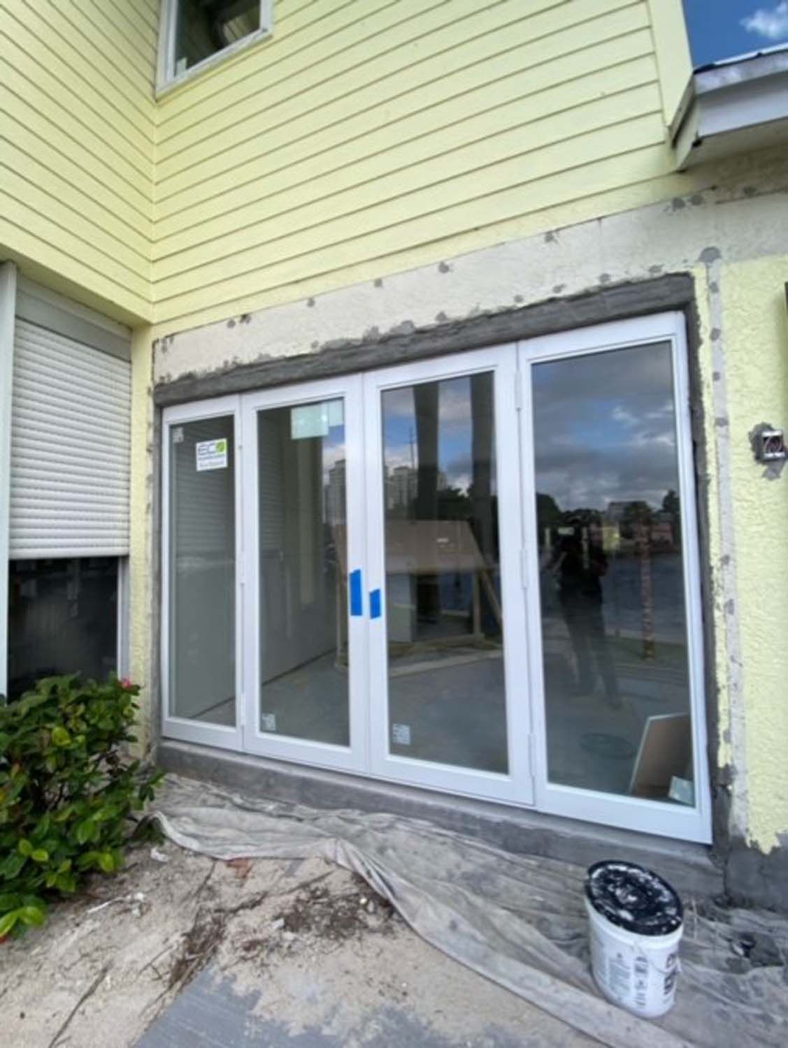 A yellow house with white sliding glass doors is being built.