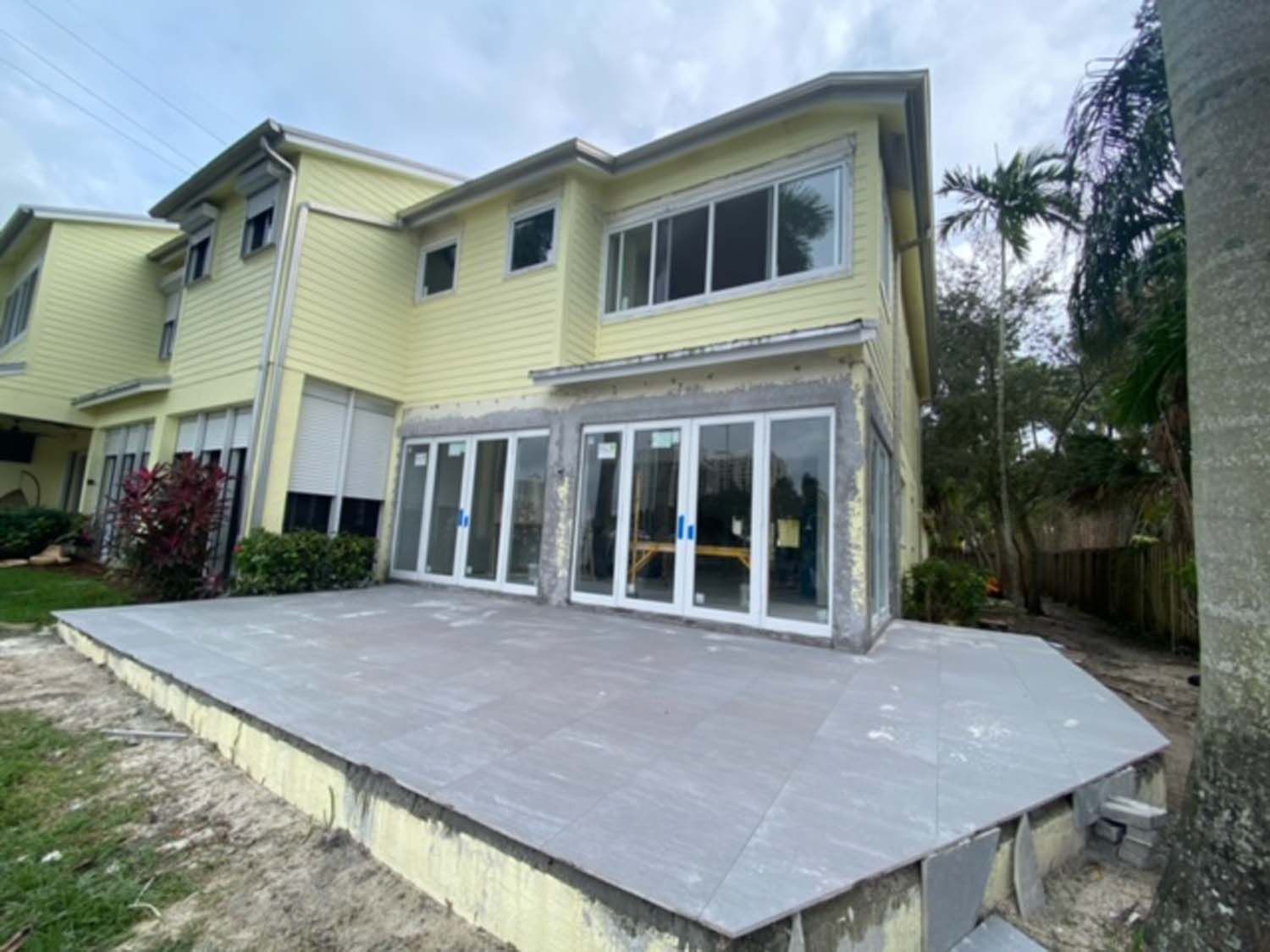 A large yellow house with a large patio in front of it.