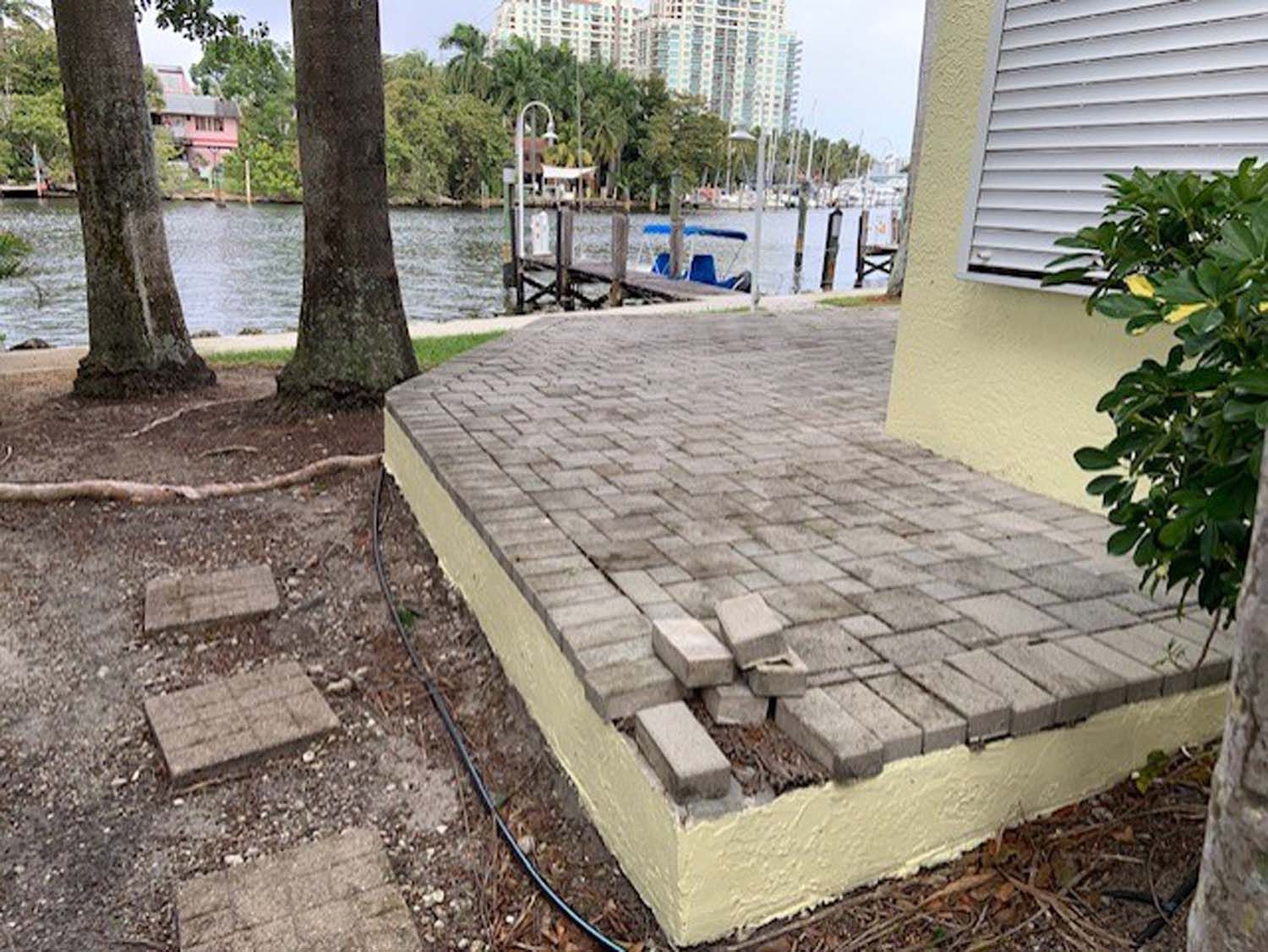 A brick walkway next to a house with a dock in the background.