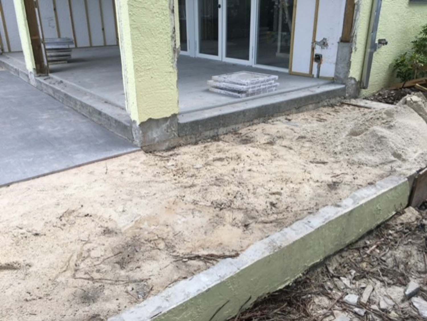 A concrete walkway is being built in front of a house.
