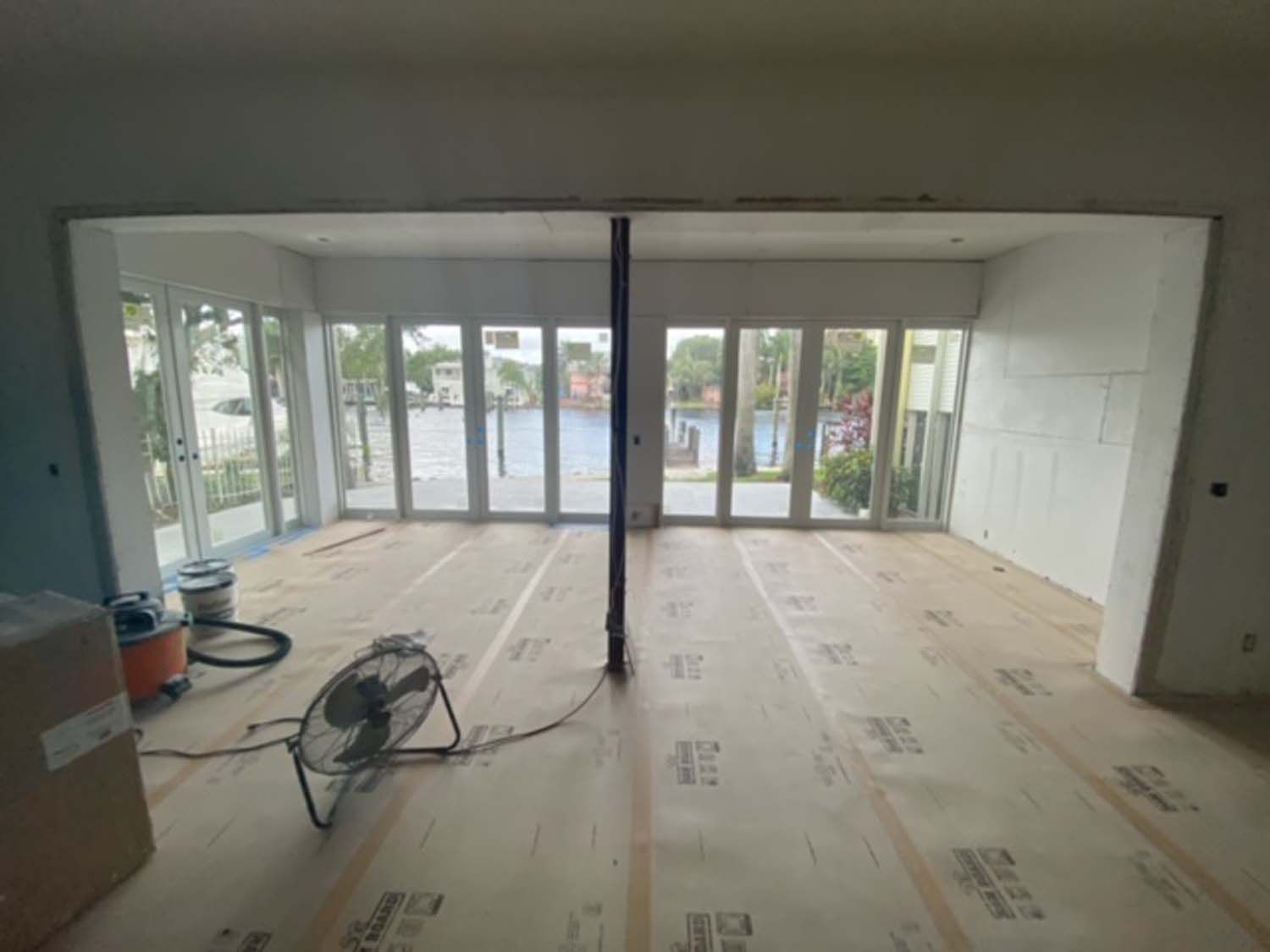 A room with a lot of windows and a fan on the floor.