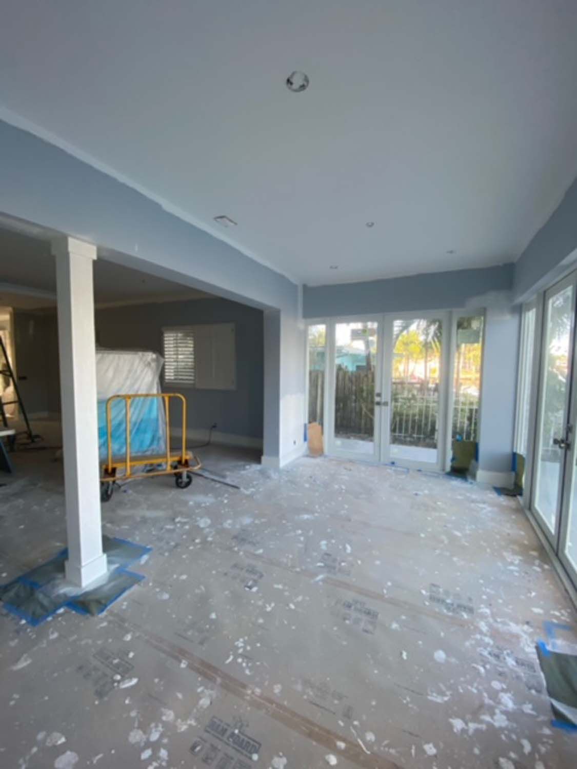 A large room with a lot of windows and doors is being painted.