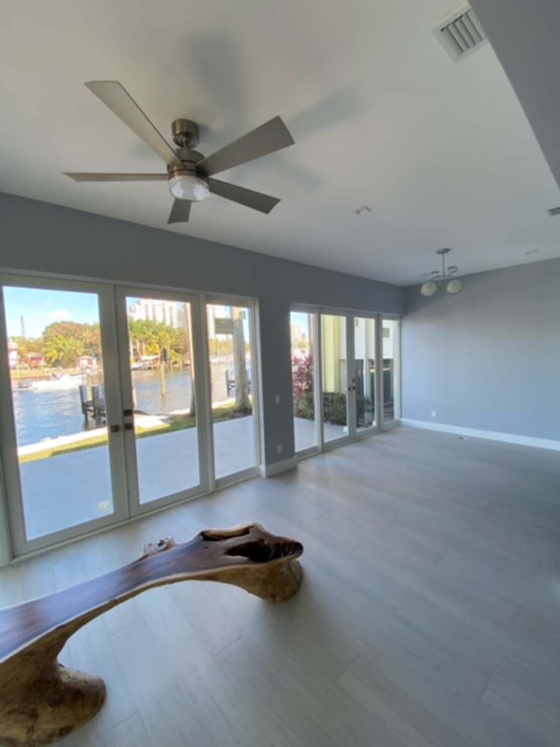 A living room with a ceiling fan and lots of windows