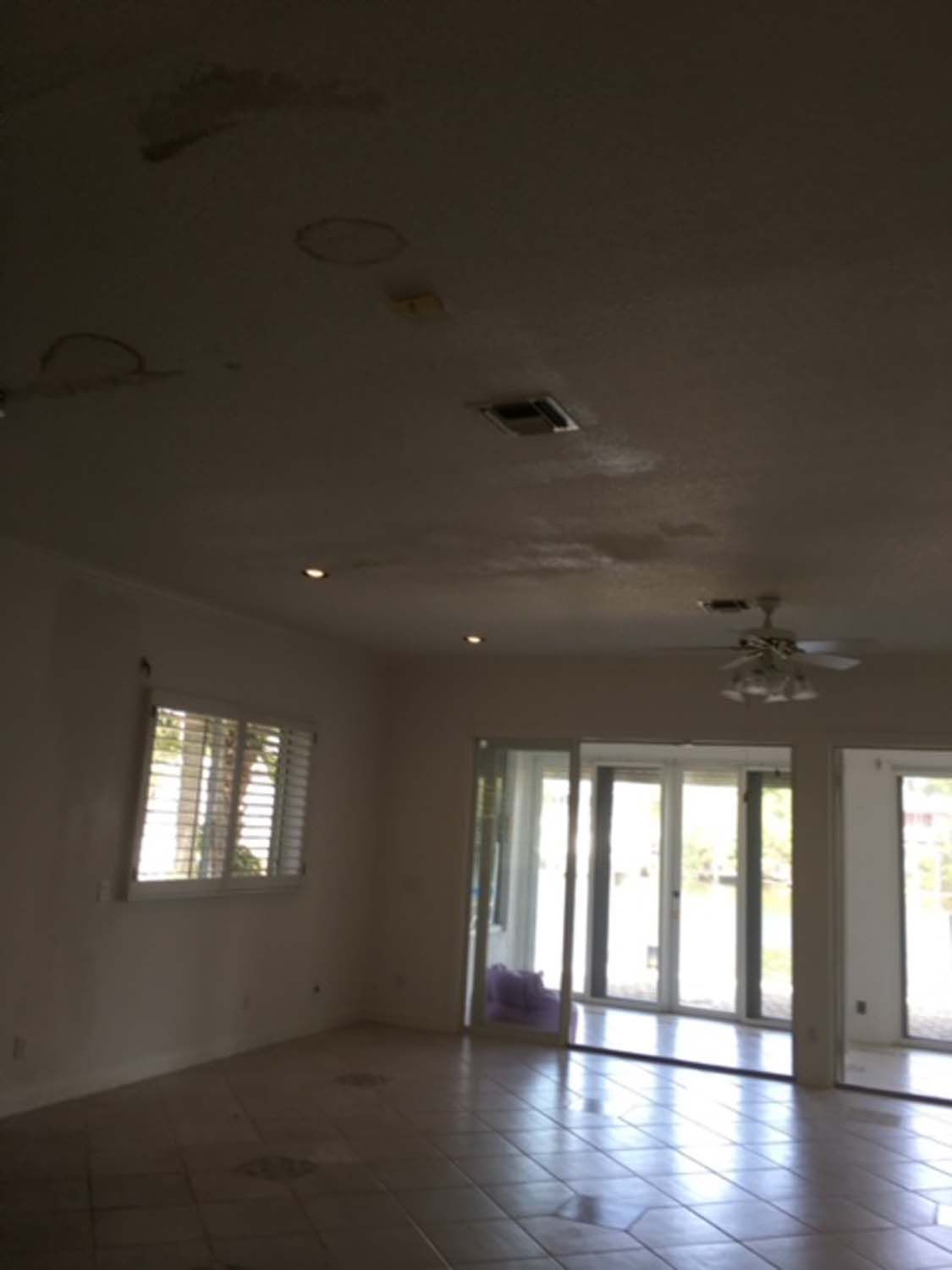 An empty room with a ceiling fan and sliding glass doors