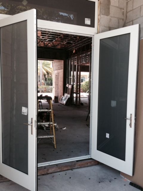 A white door with black screens is open to a building under construction