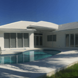 A white house with a swimming pool in front of it.