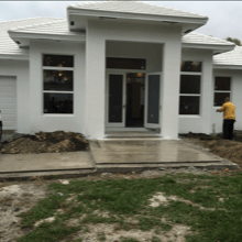 A man is standing in front of a white house.
