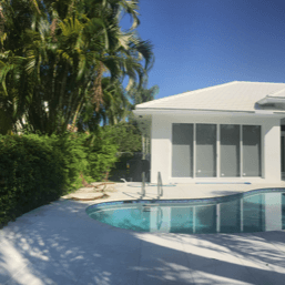 A white house with a swimming pool in front of it