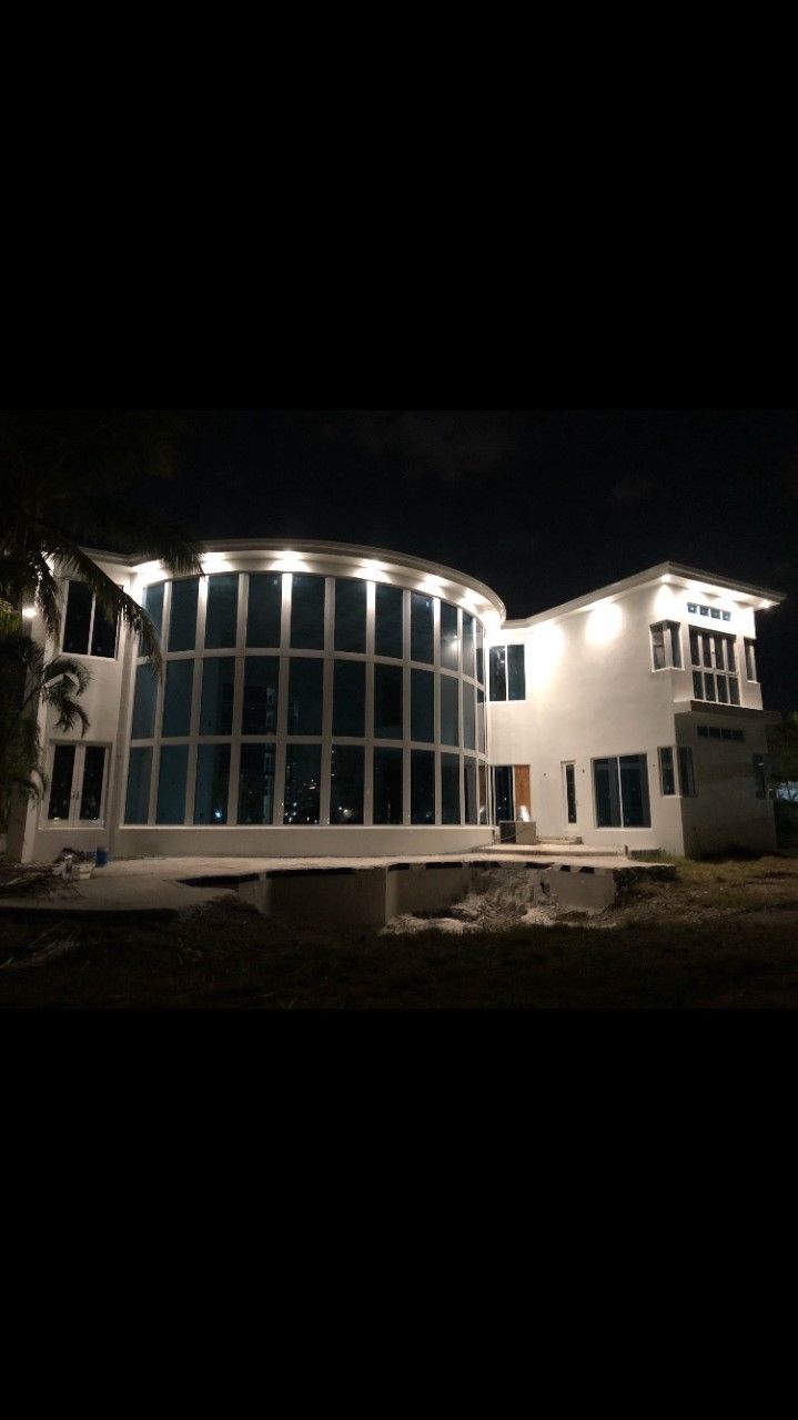 Modern building at night with a curved glass facade and white wings, lit by exterior lights