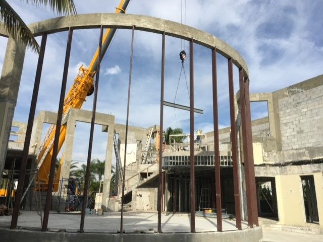 A crane is lifting a beam into a building under construction.