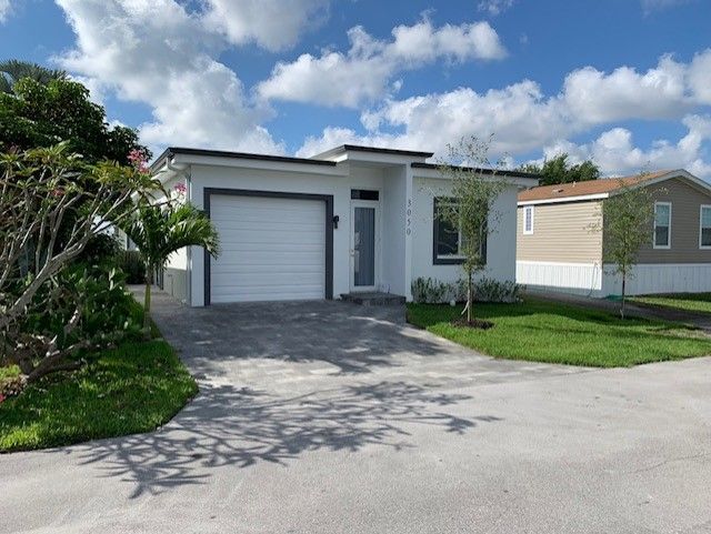 A white house with a garage and a driveway in front of it.