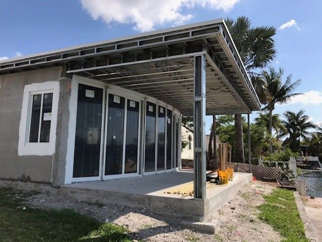 A house with a porch and a lot of windows is being built.
