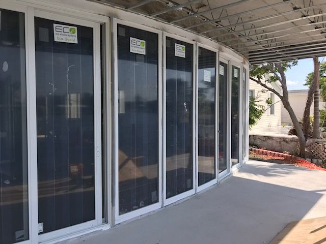 A row of sliding glass doors are being installed on a porch.