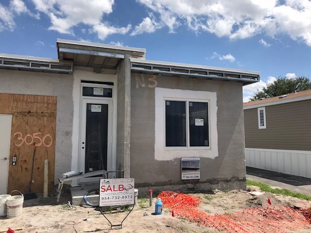 A small house is being built with a for sale sign in front of it.