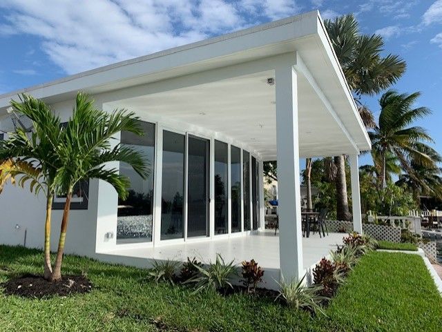 A white house with a porch and palm trees in front of it