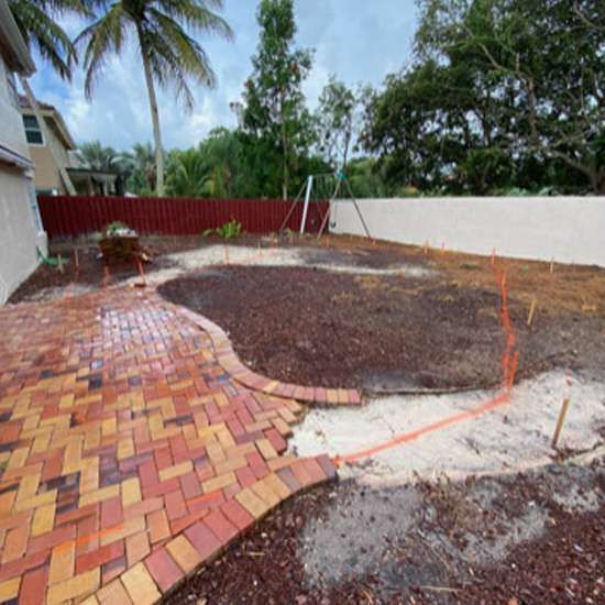 A brick walkway is being built in a backyard