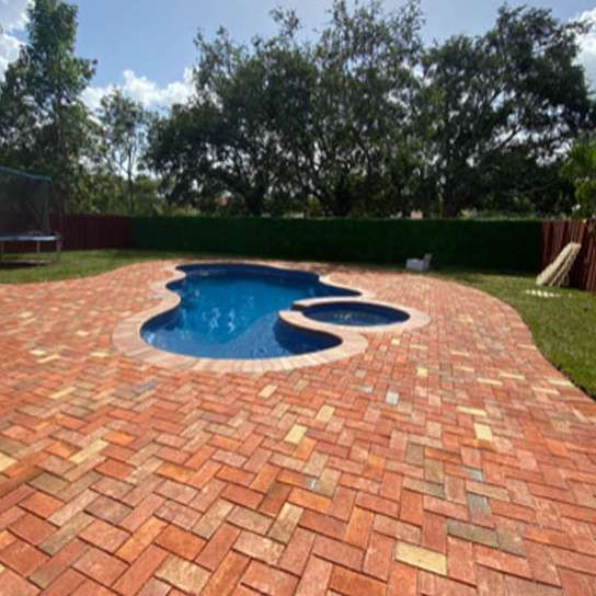 A brick patio with a swimming pool in the middle