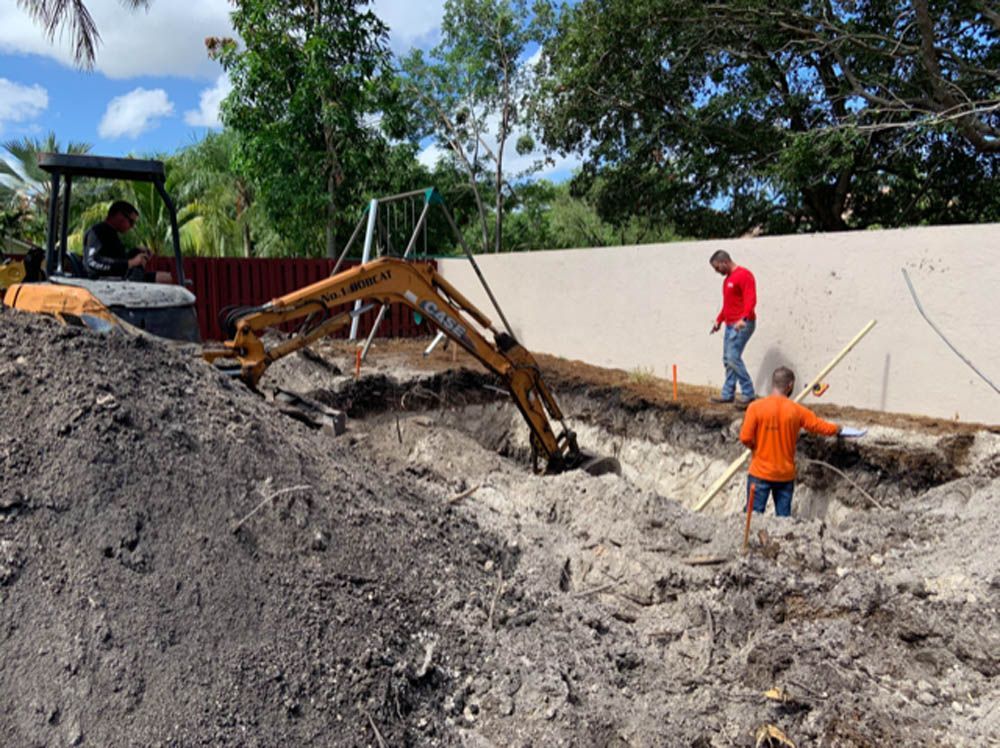 A man is standing in the dirt next to a bulldozer.