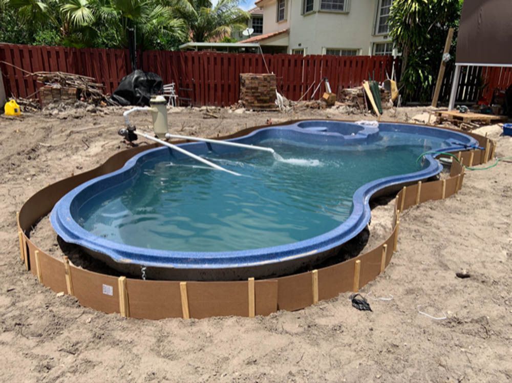 A large swimming pool is being built in a backyard.