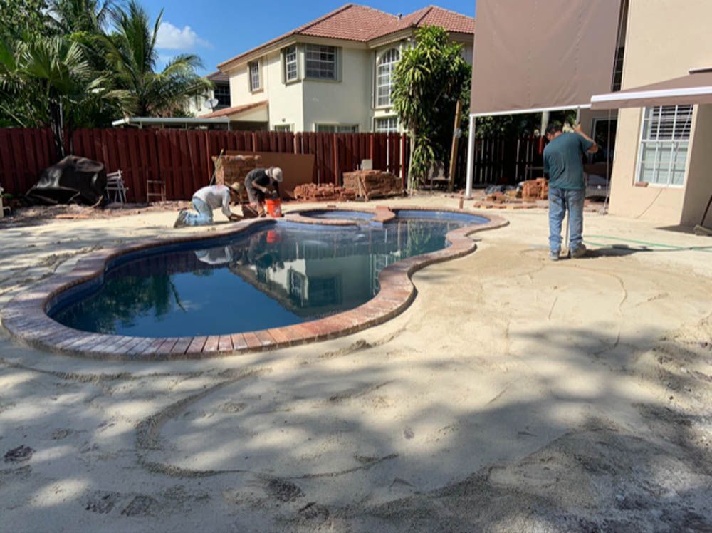 A man is standing next to a swimming pool in a backyard.