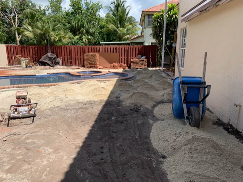 A wheelbarrow is sitting in front of a house next to a pool.