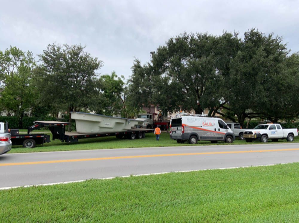 A truck is being towed down the road by a tow truck.