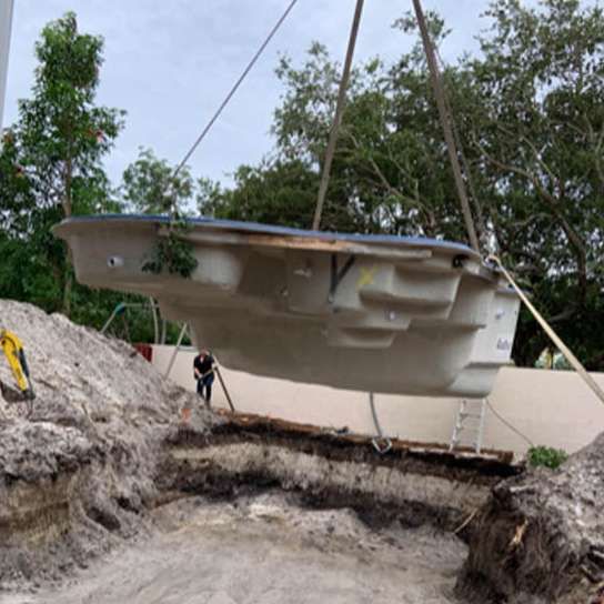 A large white swimming pool is being lifted by a crane.