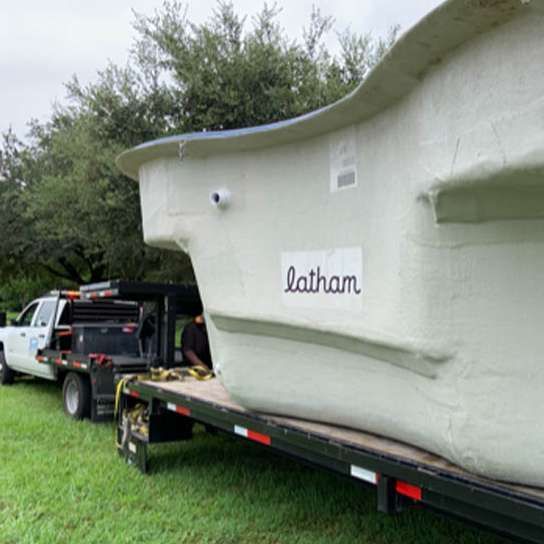 A truck is towing a large pool on a trailer.