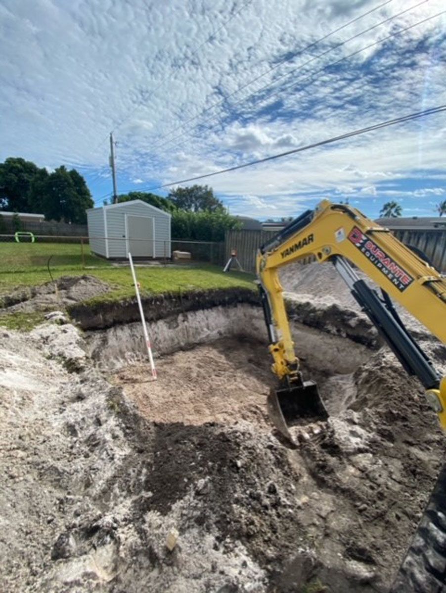 A yellow excavator is digging a hole in the dirt.