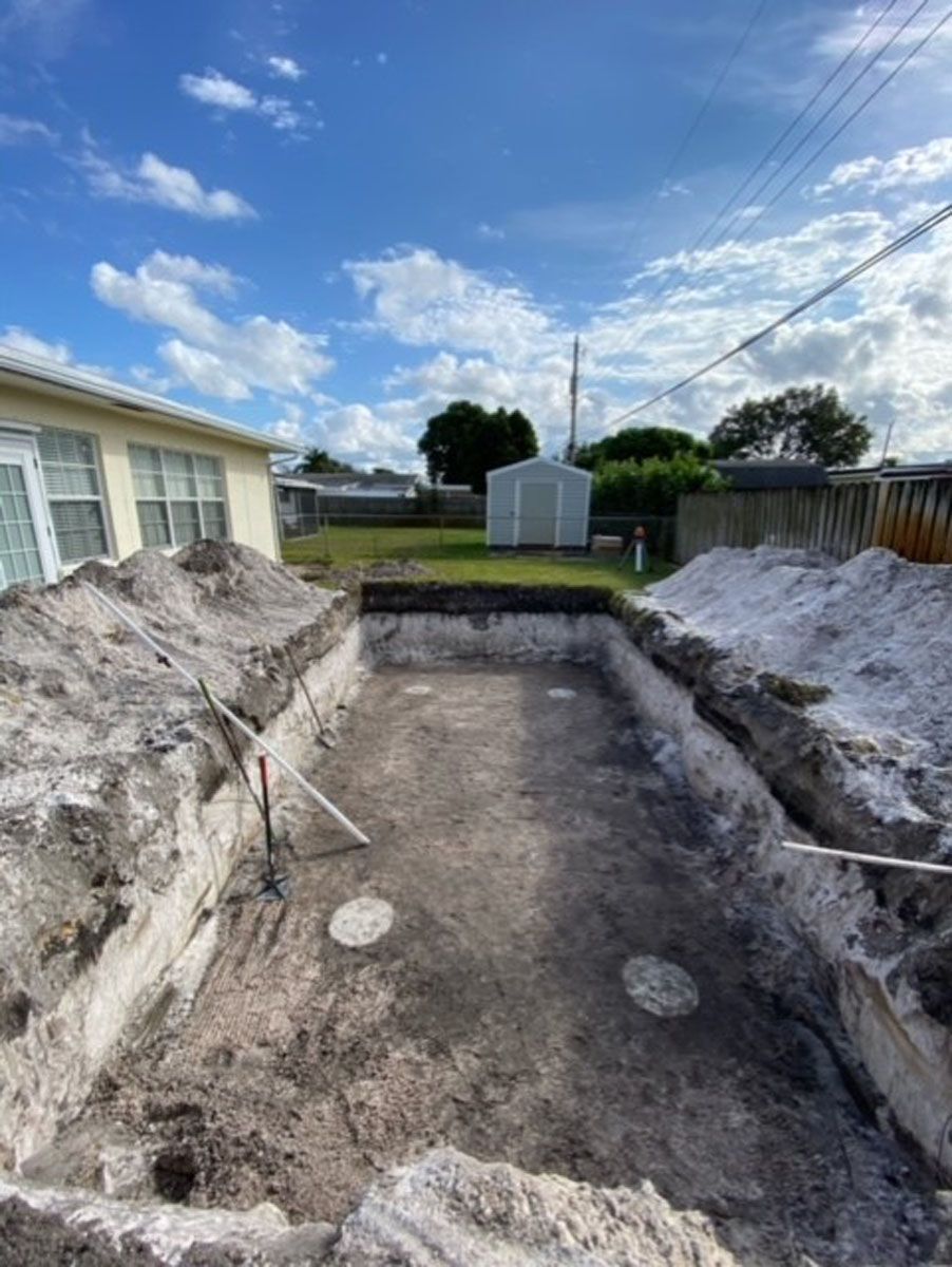 A swimming pool is being built in the backyard of a house.