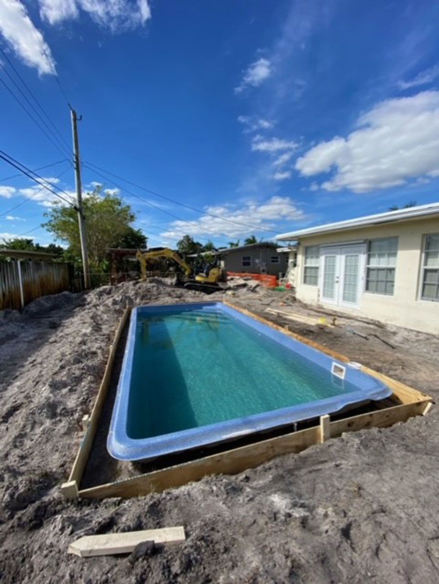 A swimming pool is being built in the backyard of a house.