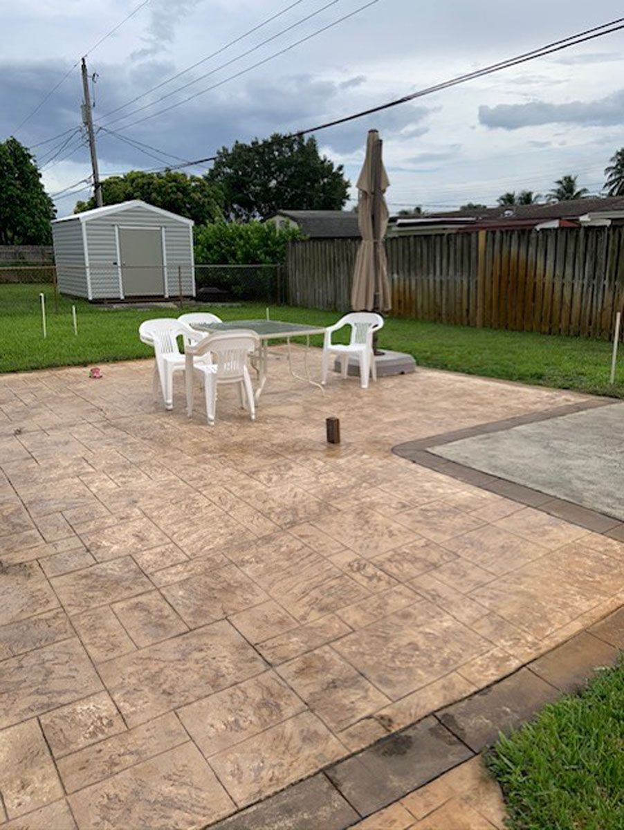 A patio with a table and chairs and a shed in the background.