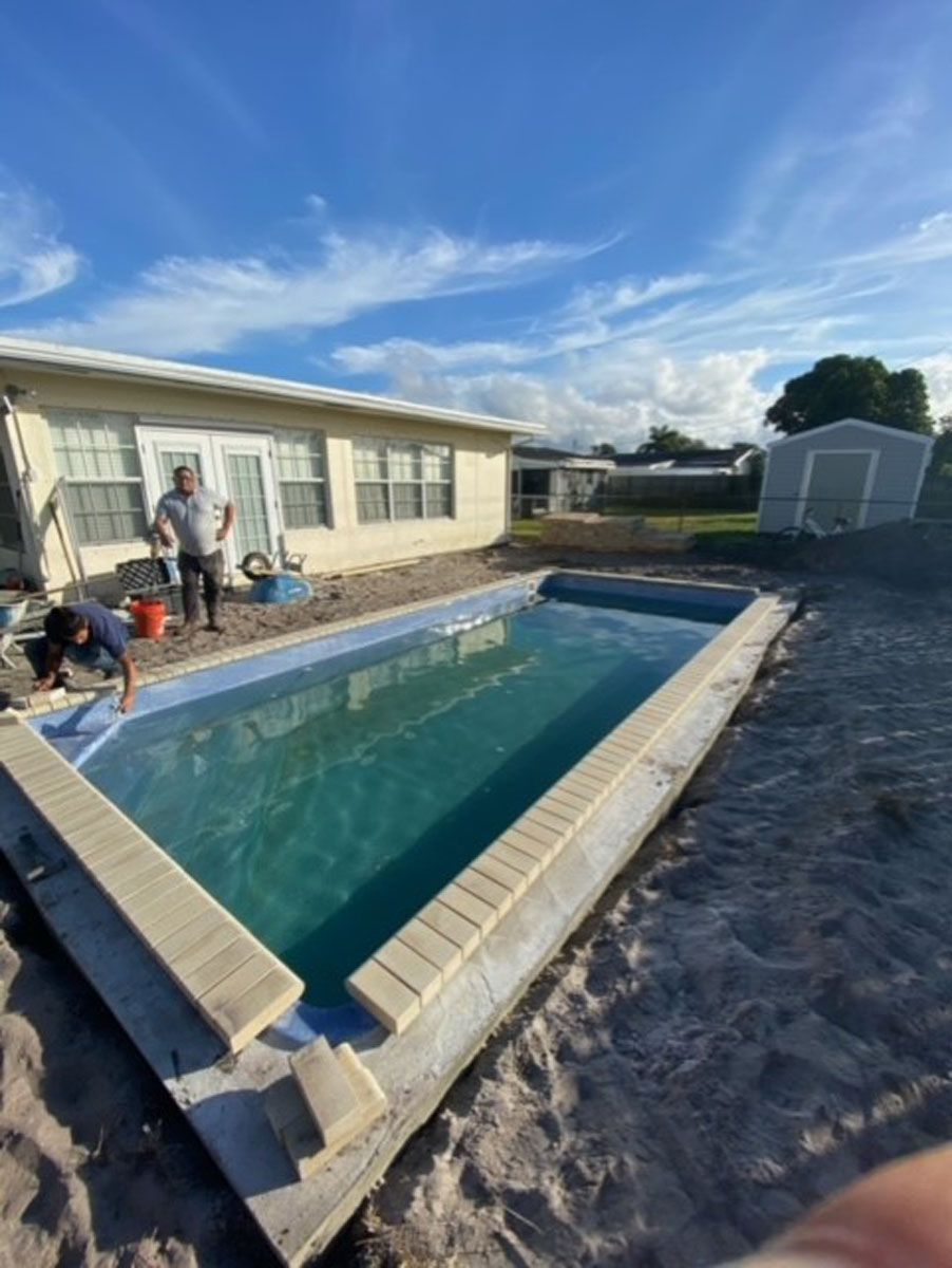 A swimming pool is being built in the backyard of a house.