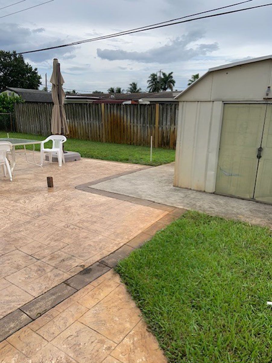 There is a shed in the backyard with a patio and chairs.