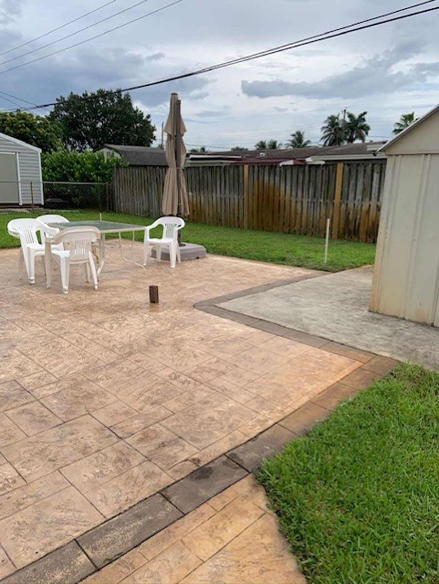 A patio with a table and chairs and a shed in the backyard.