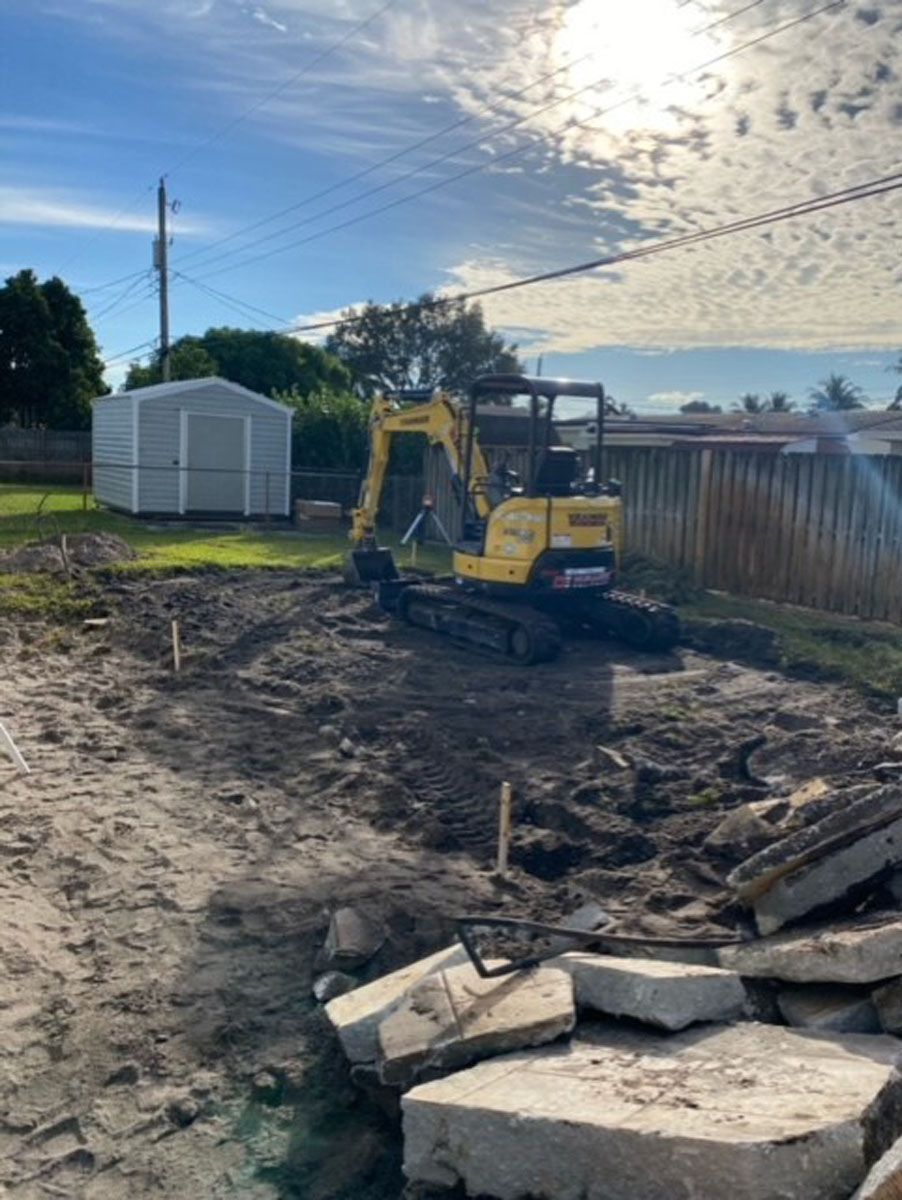 A yellow excavator is sitting on top of a dirt field.