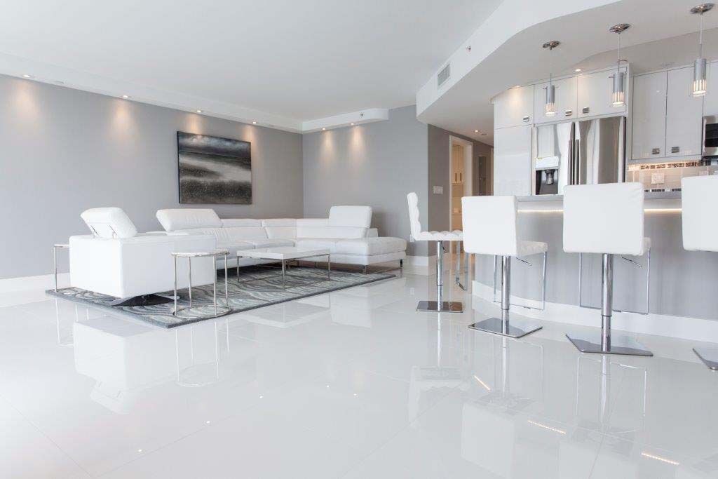A living room with a white couch , chairs , and a kitchen.