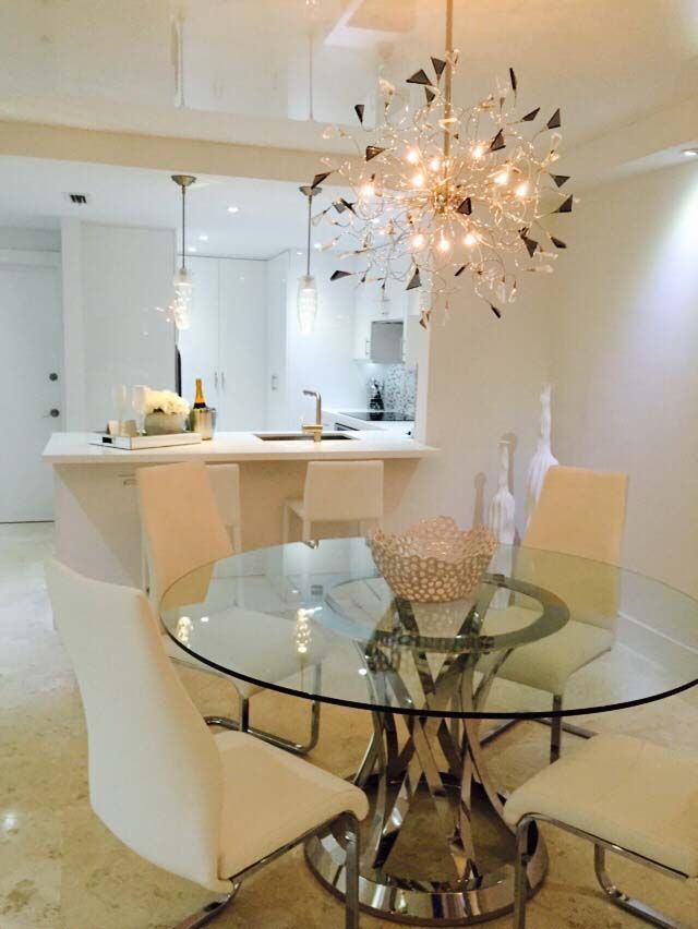 A dining room with a glass table and white chairs