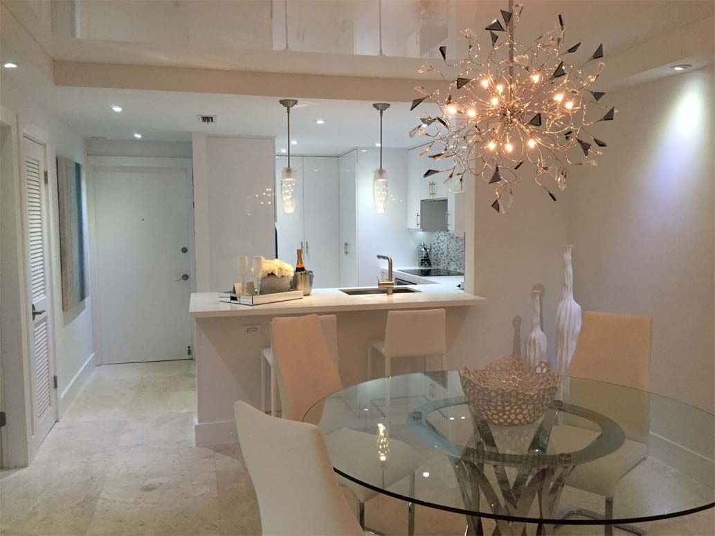 A dining room with a glass table and chairs and a chandelier.
