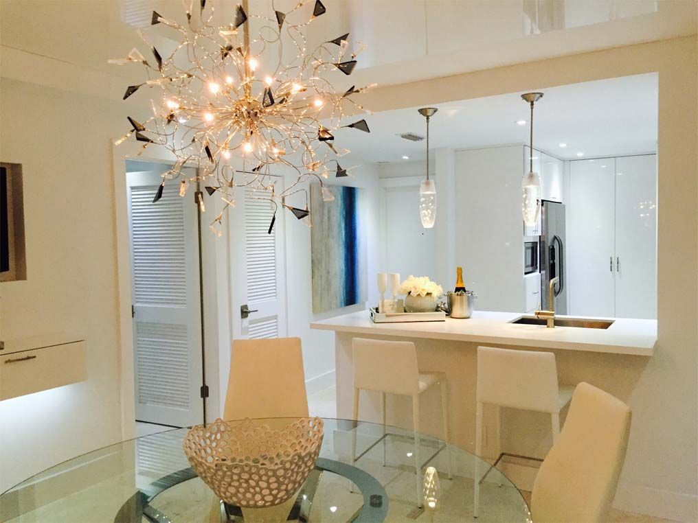 A dining room with a glass table and chairs and a chandelier