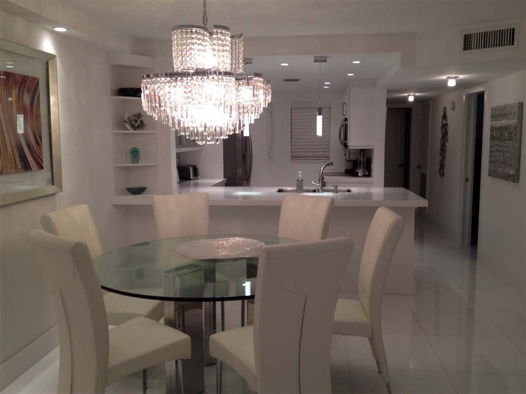 A dining room with a glass table and chairs and a chandelier