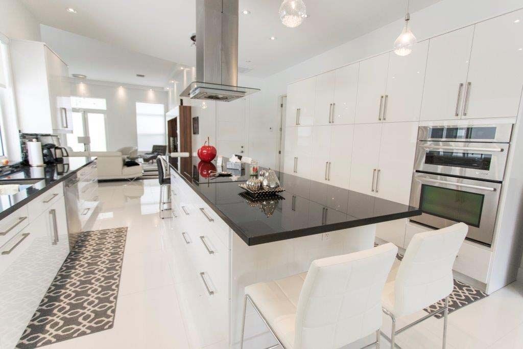 A kitchen with white cabinets , black counter tops , and stainless steel appliances.