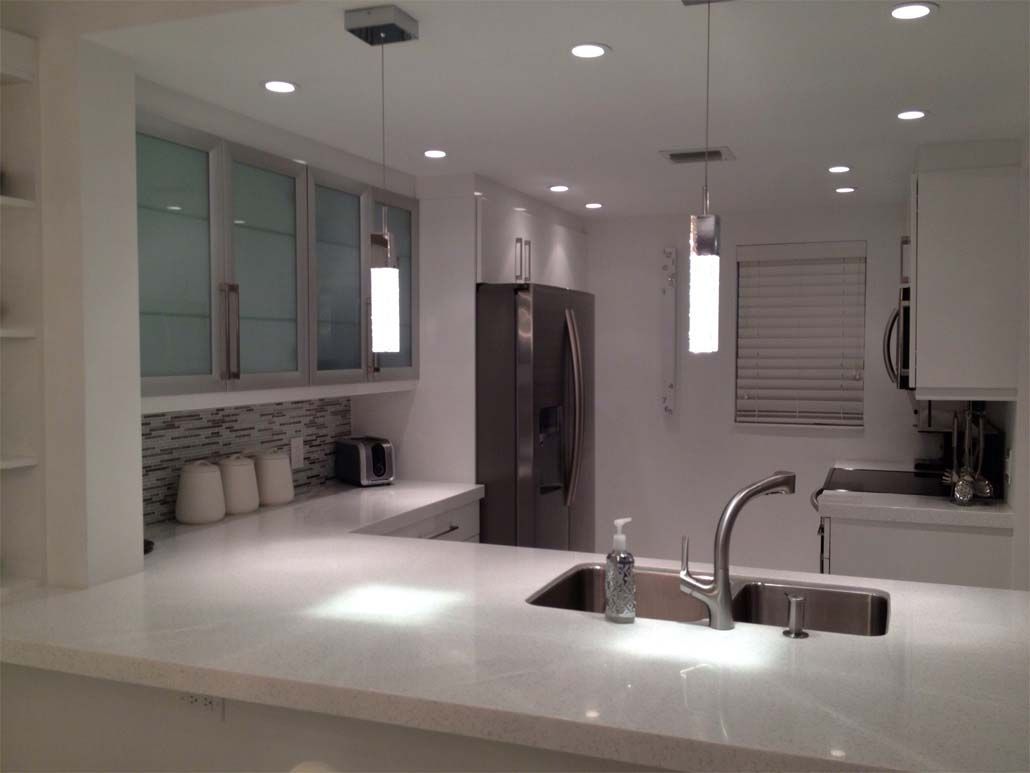 A kitchen with white cabinets a sink and a refrigerator
