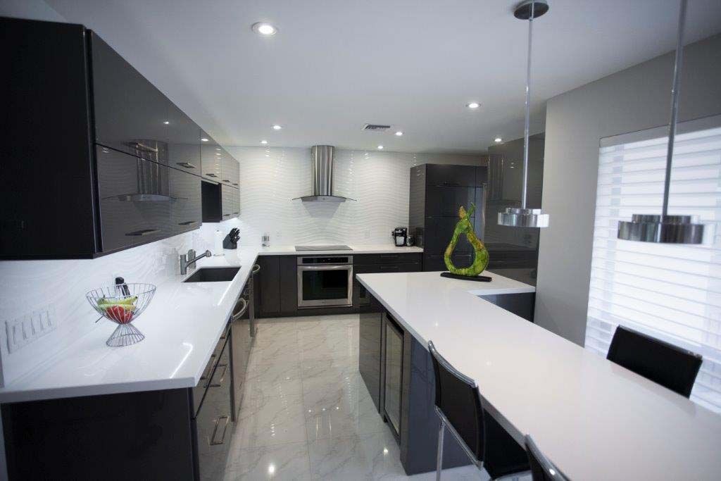 A kitchen with black cabinets and white counter tops and a large island.