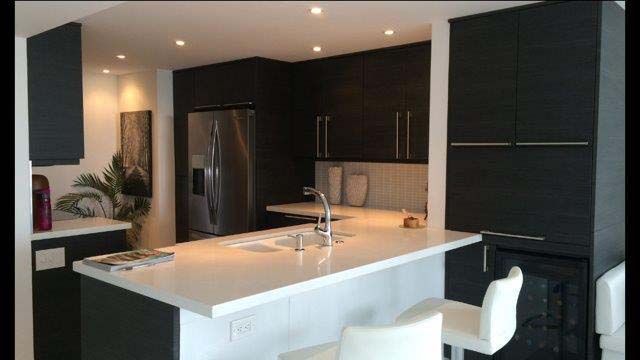 A kitchen with black cabinets and white counter tops