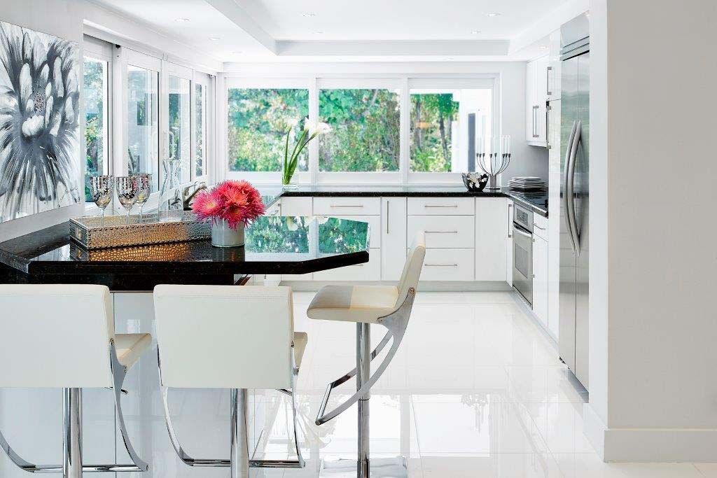 A kitchen with white cabinets , stainless steel appliances , and a large island.
