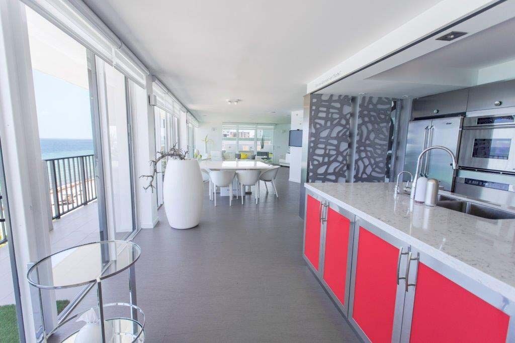 A kitchen with red cabinets and a table with a view of the ocean.